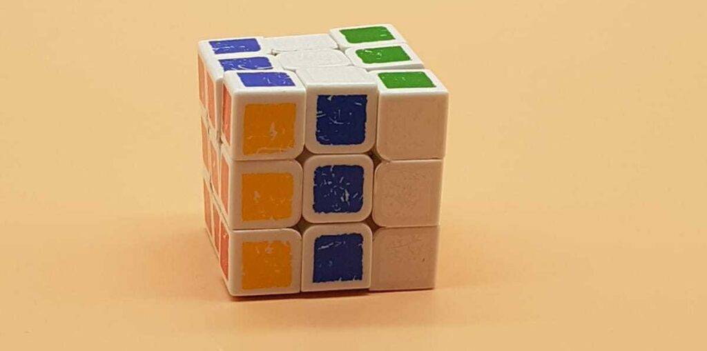 Ein getesteter Speedcube weist mehrere Farben in einer Reihe auf und liegt vor einem pfirsichfarbenen Hintergrund.