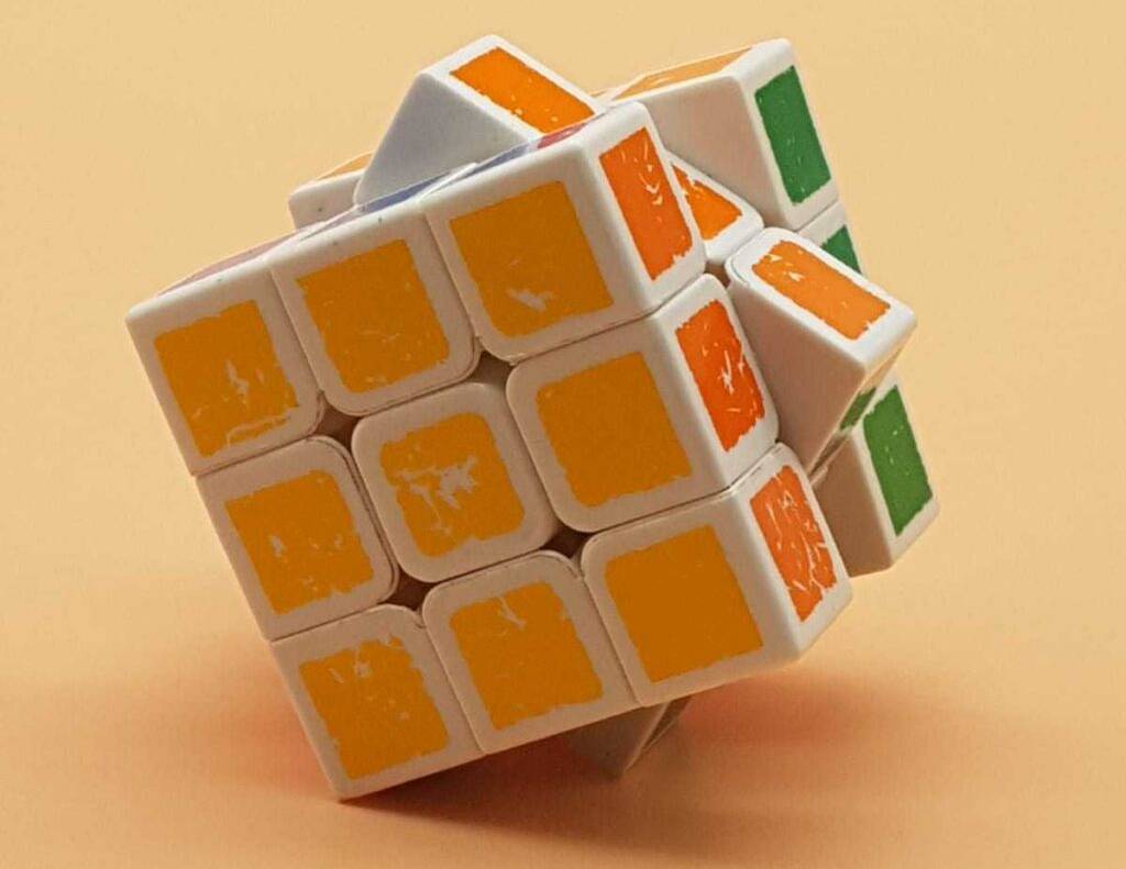 Nahaufnahme eines getesteten Speedcube, der auf einer Seite nur die gelbe Farbe aufweist und auf einem pfirsichfarbenen Untergrund liegt