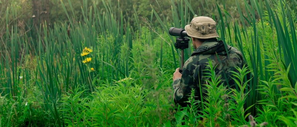 Mann beobachtet mit einem Spektiv Vögel in der Natur.