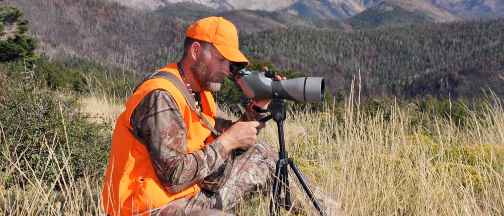 Jäger in den Bergen schaut durch ein Spektiv.