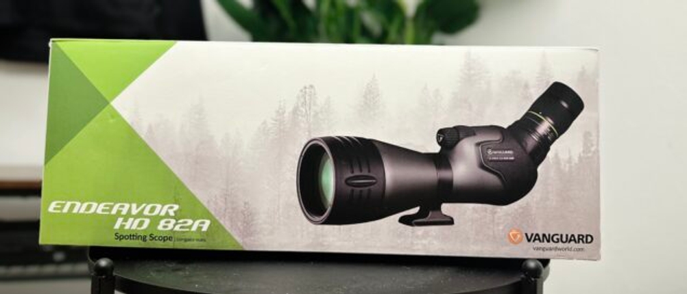 Die Verpackung des Vanguard Endeavor HD 82A Spektivs steht auf einem Tisch. Das Design zeigt das Spektiv mit grün-weißen Akzenten und dem Vanguard-Logo.