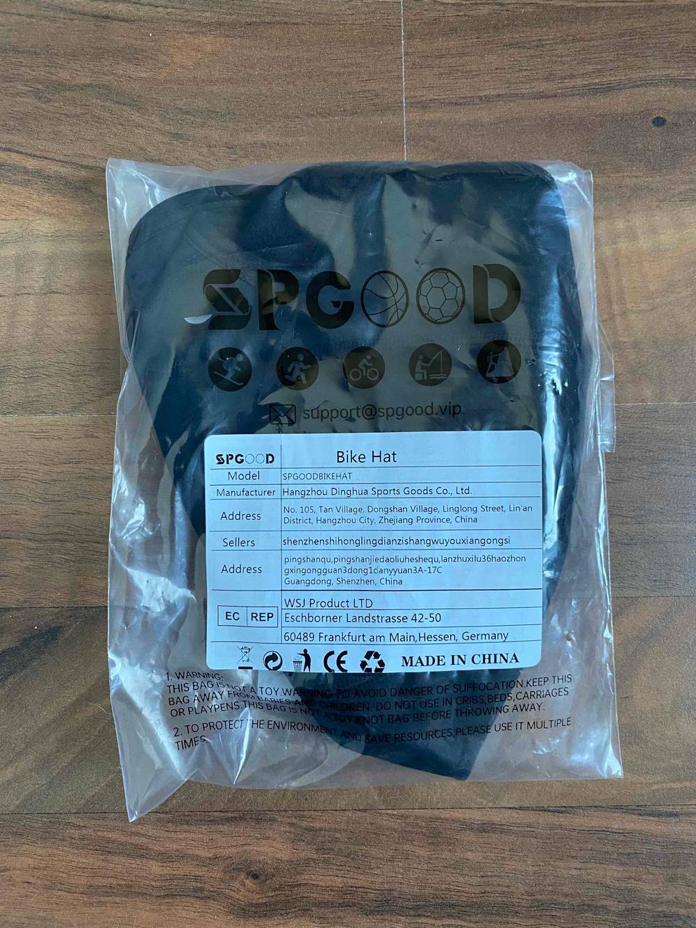 Fahrradhelm-Unterziehmütze im Test befindet sich in einer transparenten Originalverpackung auf einem Holzuntergrund.