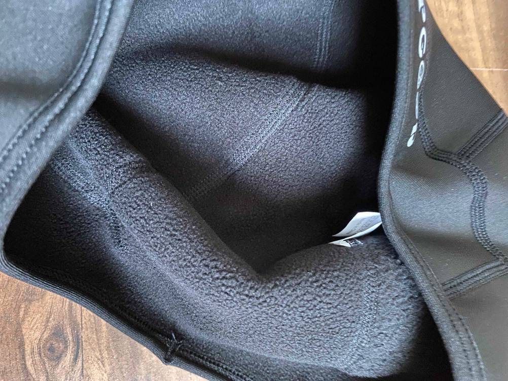 Detailansicht des flauschigen Innenfutters einer schwarzen Fahrradhelm-Unterziehmütze im Test.