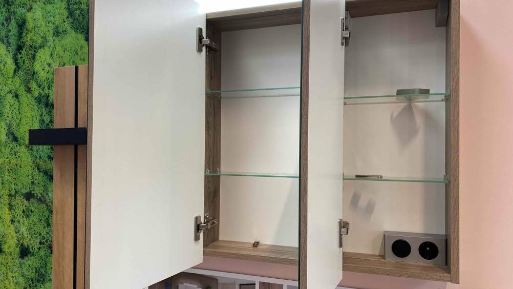 Ein getesteter Spiegelschrank mit geöffneten Türen und einer Steckdose im Inneren.