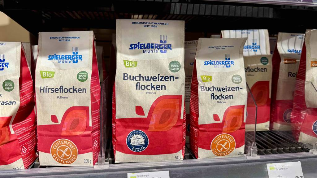 Im Test: Buchweizenflocken in mehreren 500-g-Packungen stehen neben weiteren Flockentypen in einem Verkaufsregal.