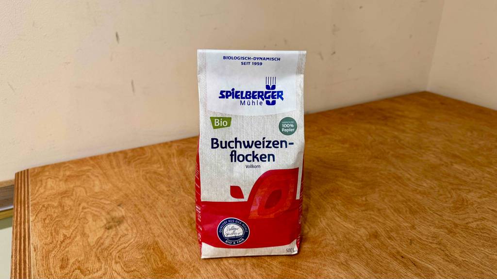 Buchweizenflocken im Test befinden sich in der 500-g-Packung auf einer Holzoberfläche.