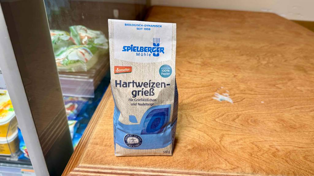 Hartweizengrieß im Test: Eine 500-g-Packung steht auf einer Holzfläche neben dem Kühlschrank eines Lebensmittelgeschäfts.