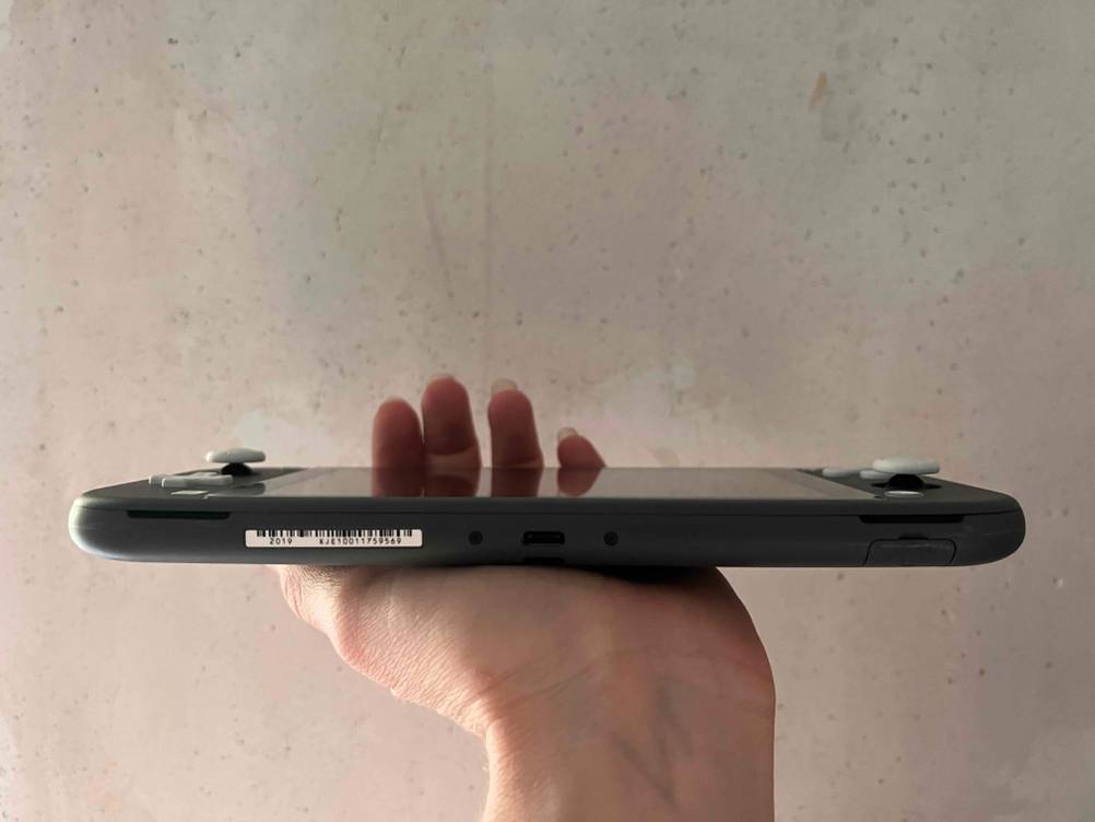 Im Test: Seitenansicht einer Spielekonsole die eine Hand vor eine helle Wand hält.