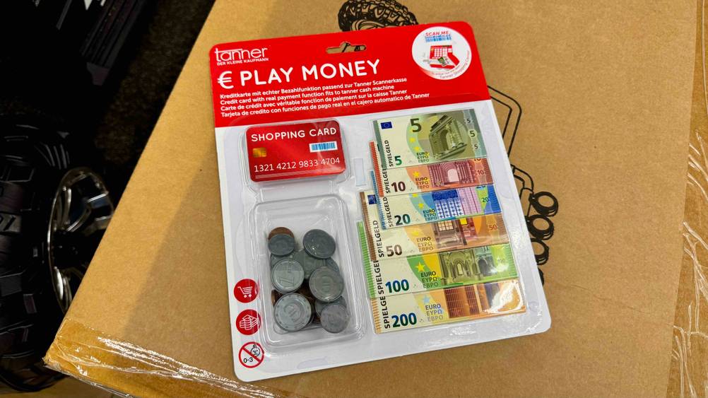 Das getestete Spielgeld in der transparenten Originalverpackung auf einem Karton.