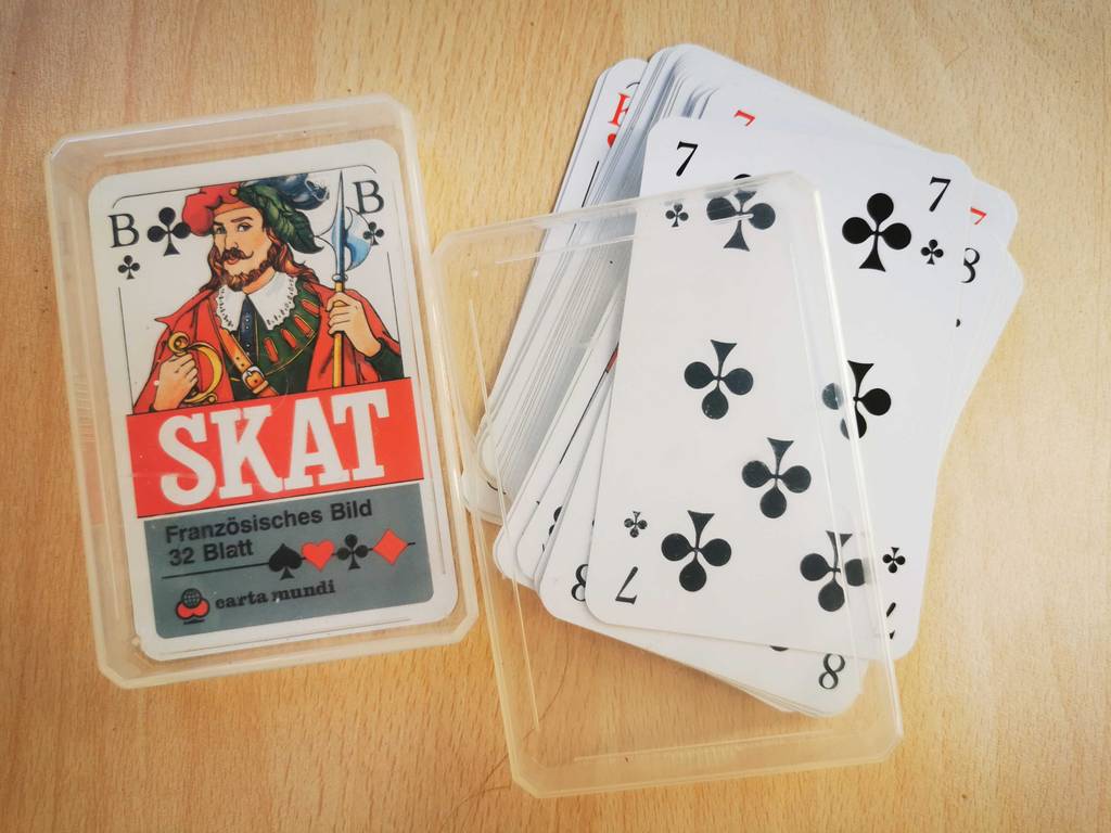 Ein Stapel Spielkarten für Skat liegt zum testen auf einer hellen Holzfläche.