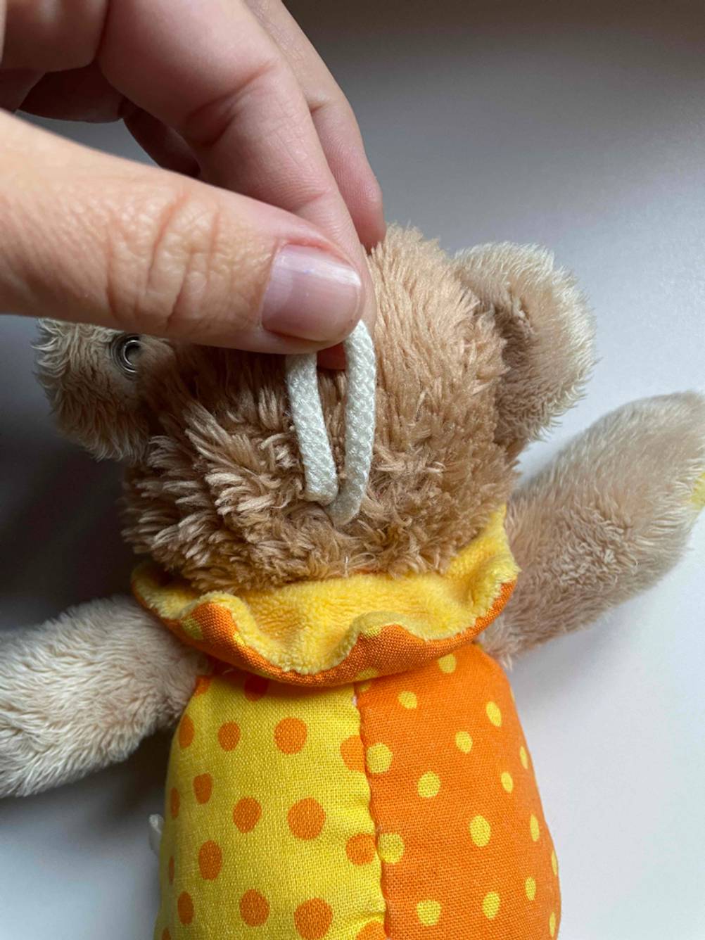 Eine Hand hält die Aufhängung hinten an einer Spieluhr für Babys im Test.