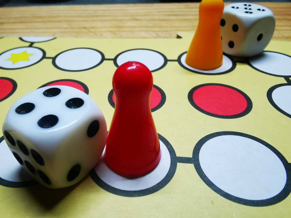 Die getesteten Spielwürfel liegen neben den Spielfiguren auf einem Spielebrett.