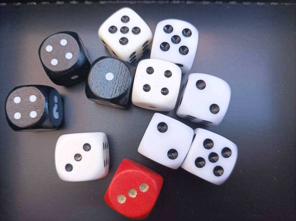 Viele unterschiedliche Spielwürfel im Test auf einer dunklen Fläche.