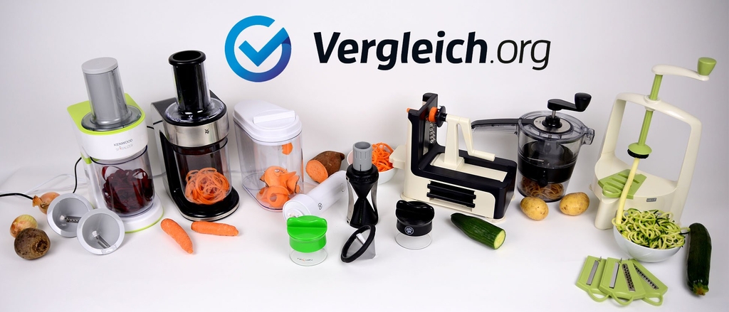 Zahlreiche Spiralschneider stehen neben Gemüse in einer Reihe vor einem weißem Hintergrund.