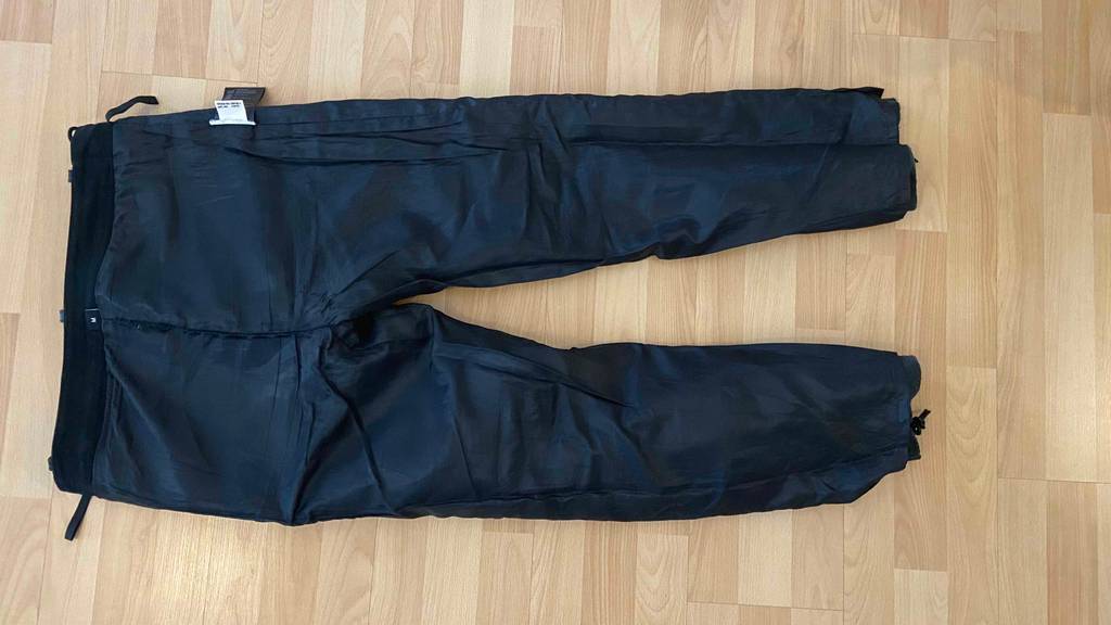 Lederhose im Test: eine Lederhose liegt auf Links gedreht, mit Sicht auf das schwarze Innenfutter auf einem Parkettboden.