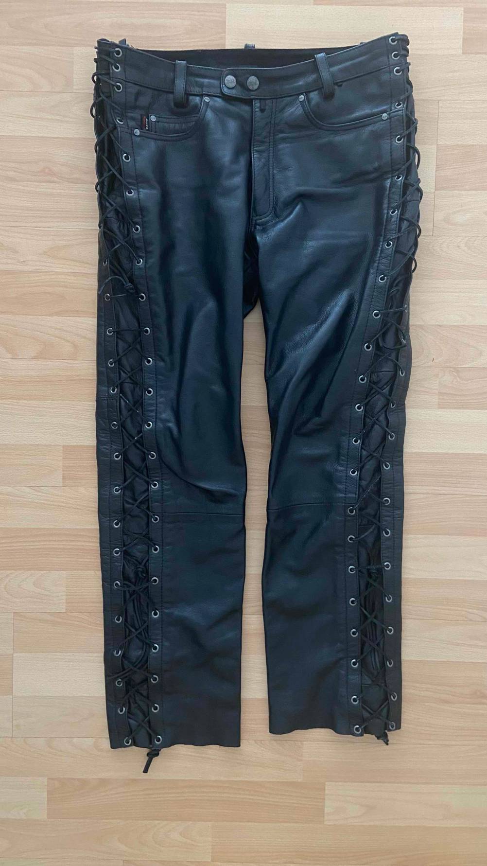Vorderseite einer getesteten Lederhose, die auf einem hellen Laminatboden liegt.