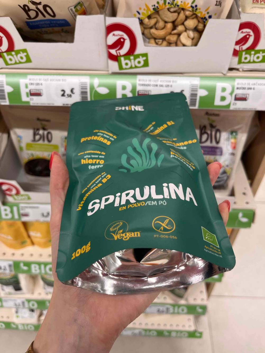 In der Hand befindet sich eine Packung getestetes Spirulina-Pulver.