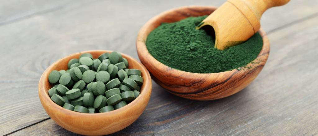 Spirulina-Tabletten-Test: In zwei Holzschälchen befinden sich Spirulina-Tabletten und Spirulina-Pulver. 