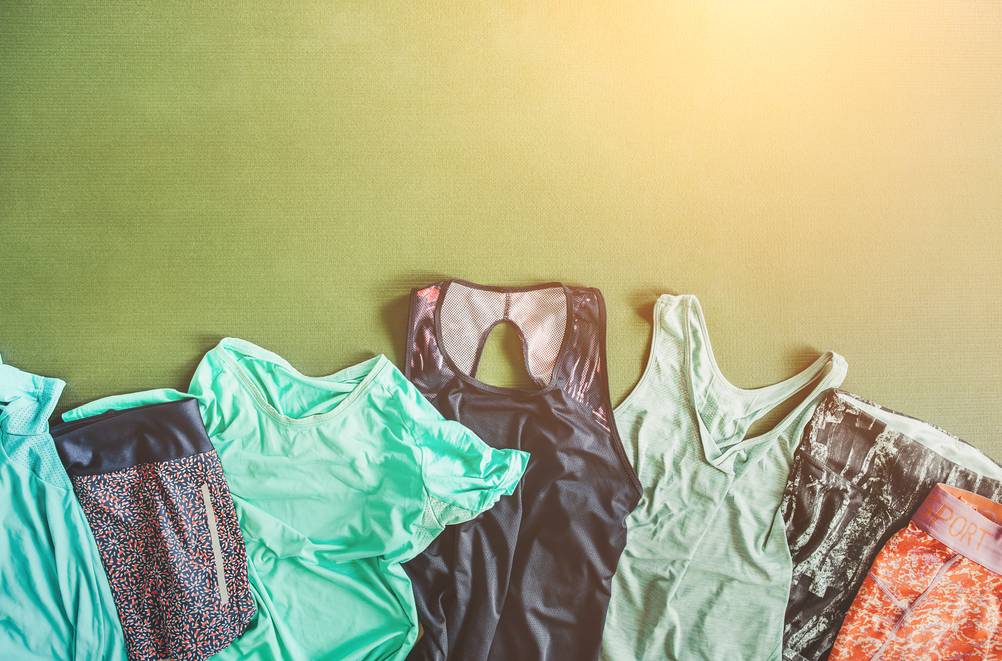 Mehrere Stücke Funktions-Sportkleidung, die zerknittert und schmutzig sind, liegen nebeneinander ausgebreitet auf einer Sportmatte.