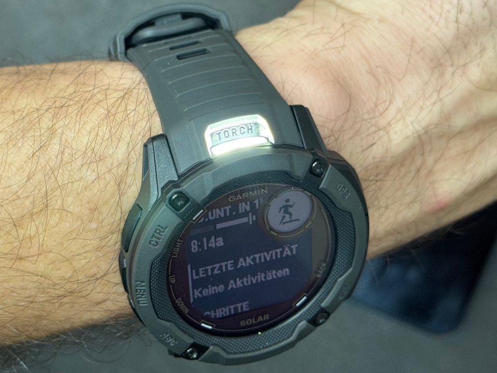 Eine Person trägt die Garmin-Sportuhr im Test am Armgelenk, die seitliche LED leuchtet.