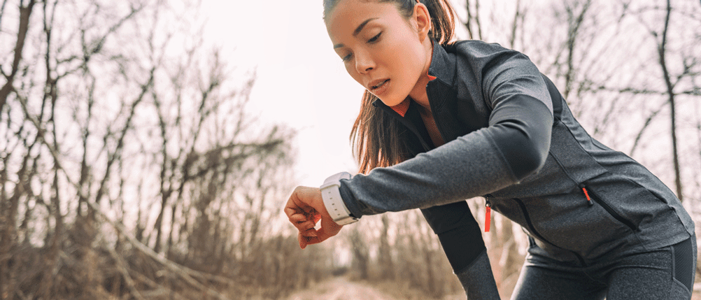Sportuhr-Test: Frau ist im Wald und schaut auf ihre Uhr