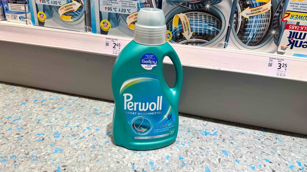 Getestet: Vor einem Regal auf dem Boden steht eine Flasche Sportwaschmittel.
