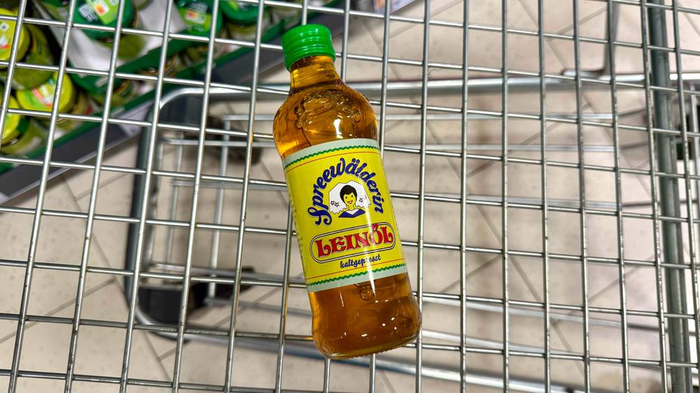 In einem Einkaufswagen liegt eine Flasche des Spreewälder Leinöls im Test.