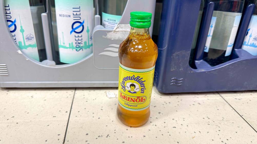 Eine Flasche des getesteten Spreewälder Leinöls steht vor Getränkekisten auf dem Boden.