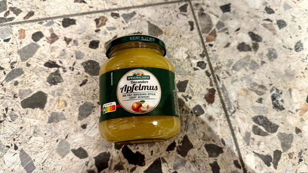 Ein Glas getestetes Apfelmus liegt auf einem Fliesenboden.