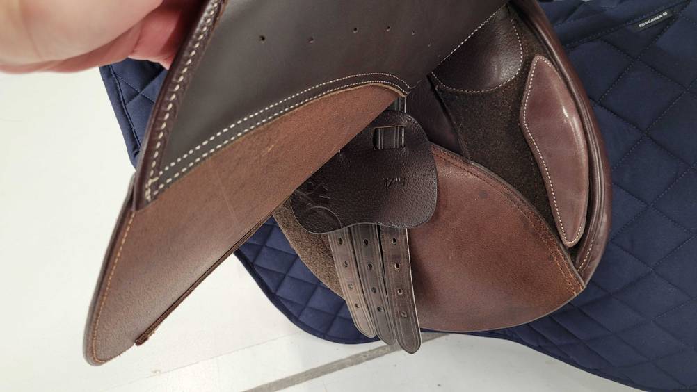 Eine Hand hält einen getesteten Springsattel aus Leder.
