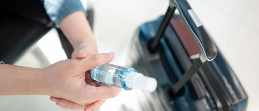 Sprühflasche 50 ml Test: Hand hält Sprühflasche über Koffer