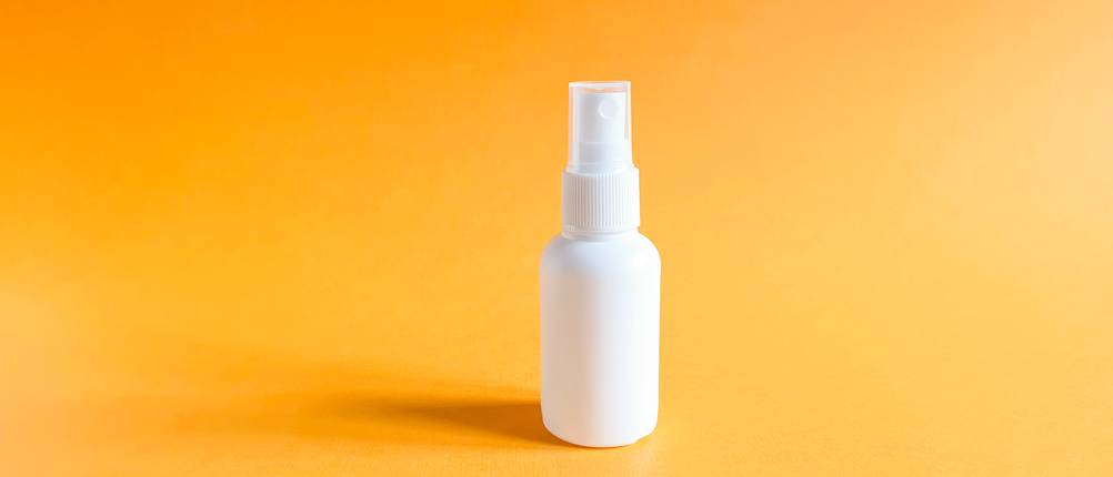 Sprühflasche 50 ml Test: weiße Plastik-Sprühflasche vor gelbem Hintergrund