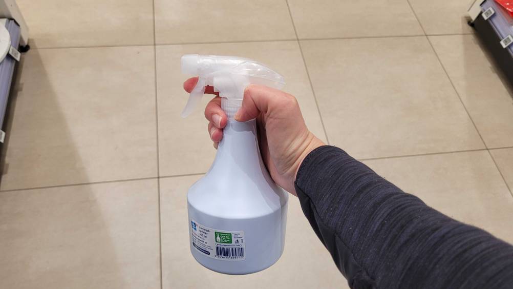 Eine Hand hält die getestete Sprühflasche hoch.