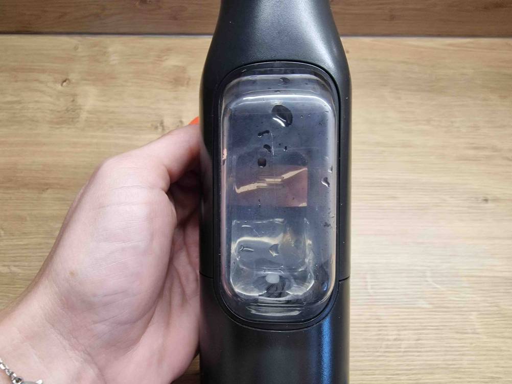 Nahaufnahme des Wasserbehälters eines getesteten Sprühwischers von einer Hand gehalten.