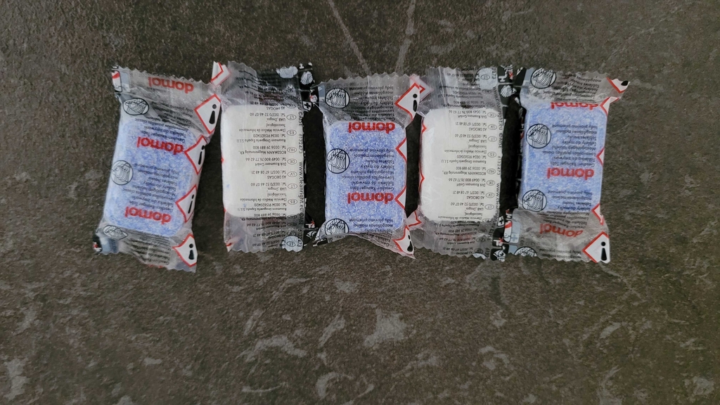 Fünf Spülmaschinentabs in Folie liegen nebeneinander auf der Arbeitsplatte.