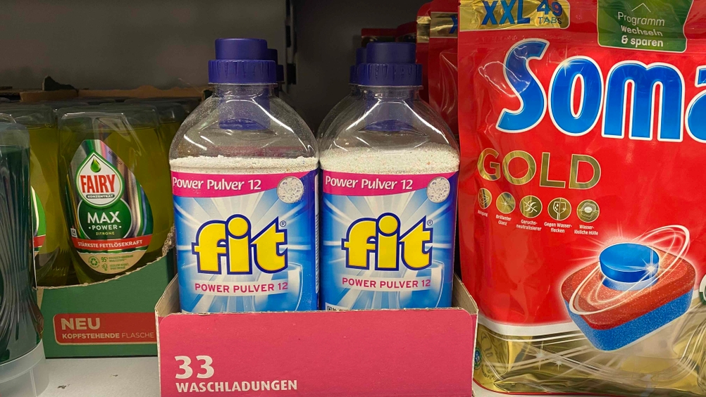 Mehrere Flaschen des getesteten Spülmaschinenpulvers stehen neben anderen Produkten in einem Regal.