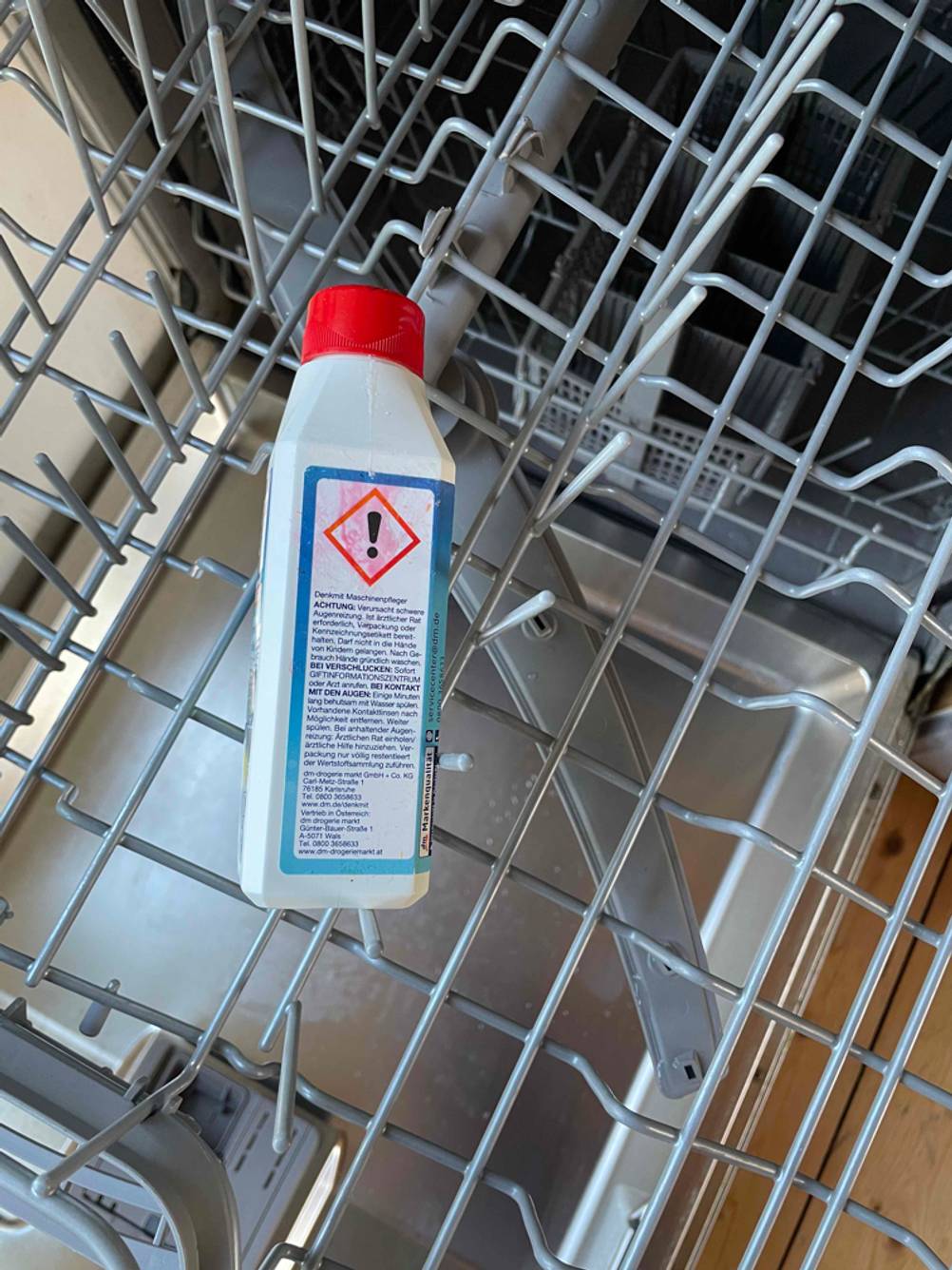 Seitenansicht einer Flasche Spülmaschinenreiniger im Test in einem Spühlmaschinenkorb.