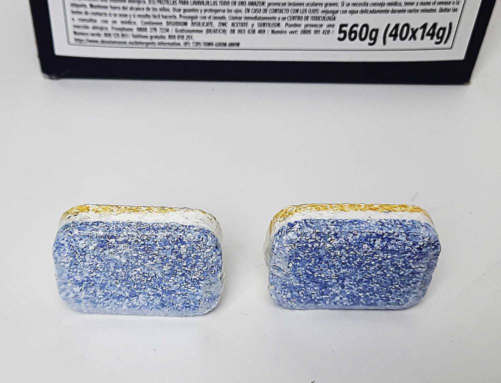 Zwei der geteseten Spülmaschinentabs ohne Plastik vor der Originalverpackung liegend.