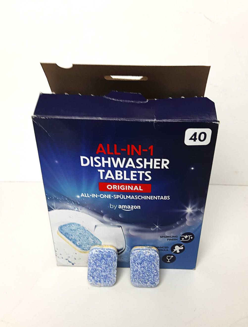 Eine Packung der Spülmaschinentabs ohne Plastik auf einer hellen Fläche, davor zwei Tabs.