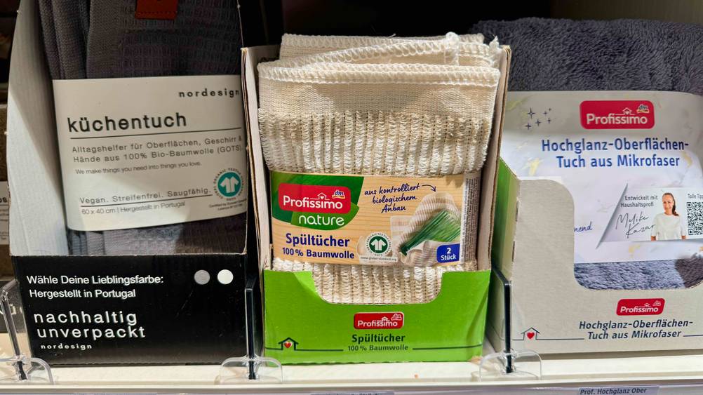 Die verpackten Spültücher im Test in einem Karton in einem Verkaufsregal neben anderen Produkten.