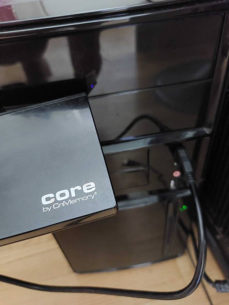 Im Test: eine getestete SSD-Festplatte Core by OnMemory vor einem schwarzen Tower-Computer.
