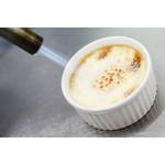 Ein Stabfeuerzeug mit Jetflamme beim Flambieren einer Crème brûlée
