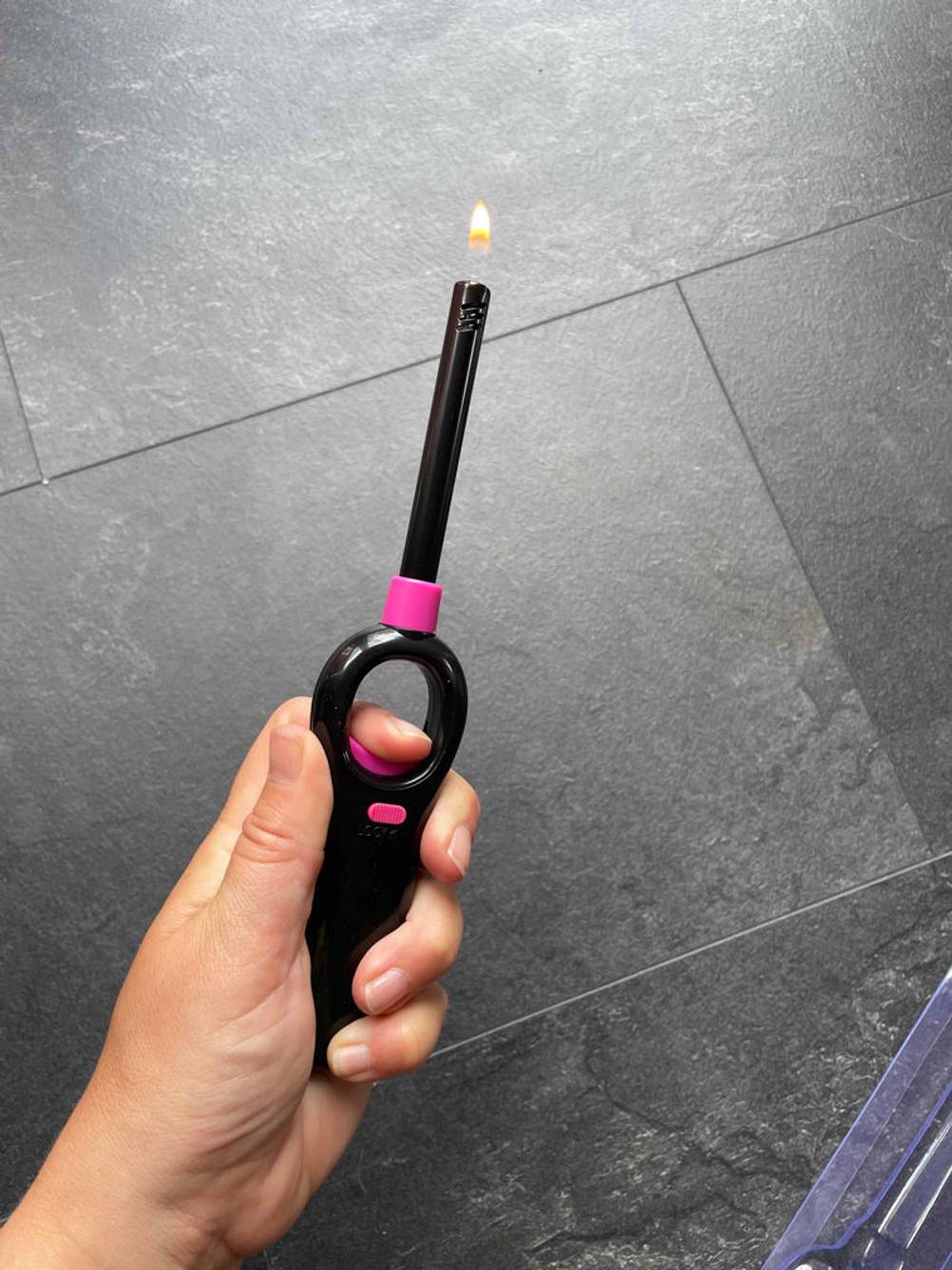 Hand zündet Stabfeuerzeug an.