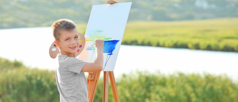 Staffelei-Kinder-Test: Kind malt Flusslandschaft auf Leinwand.