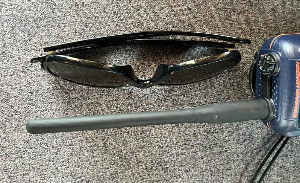 Getestetes Funkgerät von Standard Horizon befindet sich mit Fokus auf seine Antenne in Länge der daneben liegenden Sonnenbrille auf grauen Gewebe.