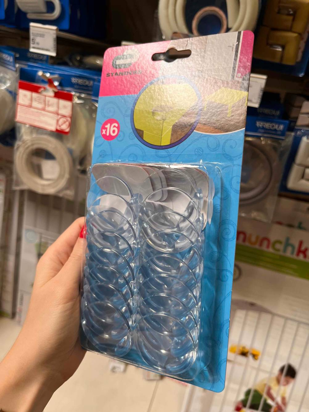 Im Test: Hand hält eine Packung Standers Kantenschutz für das Baby vor einem Verkaufsregal.
