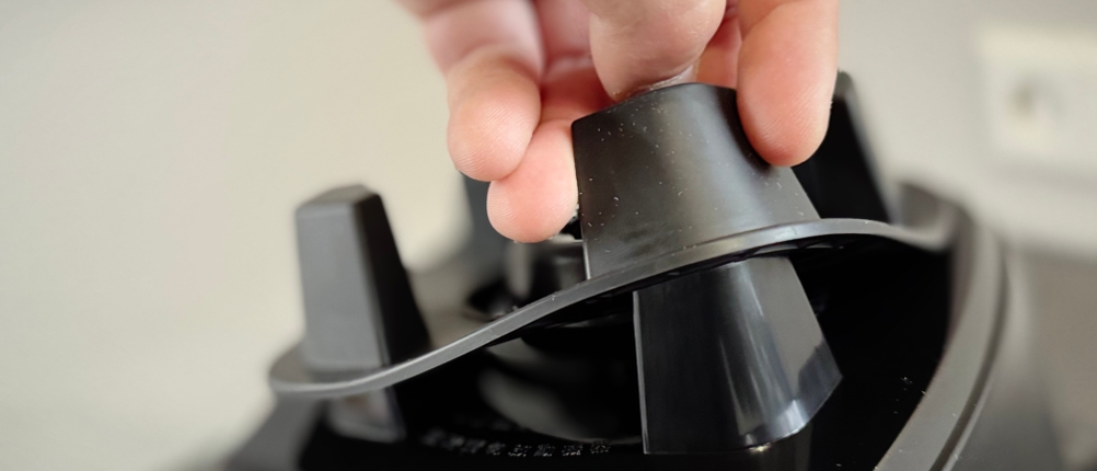 Eine Person hebt die Gummidichtung des Standfußes vom getesteten Standmixer Bosch VitaBoost.