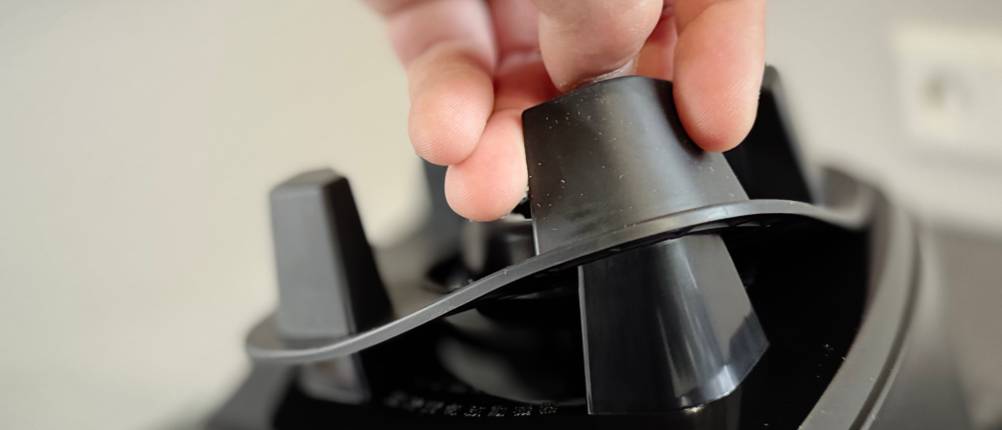 Eine Person hebt die Gummidichtung des Standfußes vom getesteten Standmixer Bosch VitaBoost.
