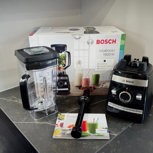 Der getestete Standmixer Bosch Vitaboost steht zusammen mit dem Zubehör vor dem Karton.