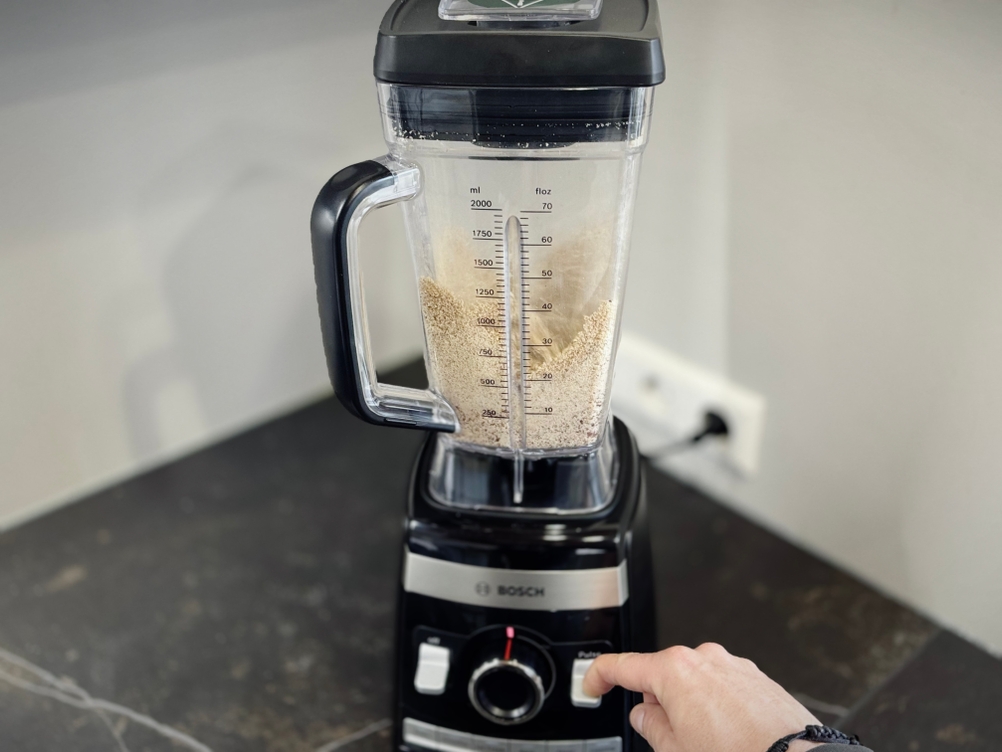 Eine Person bedient den getesteten Standmixer von Bosch in dem Haselnüsse zerkleinert werden.